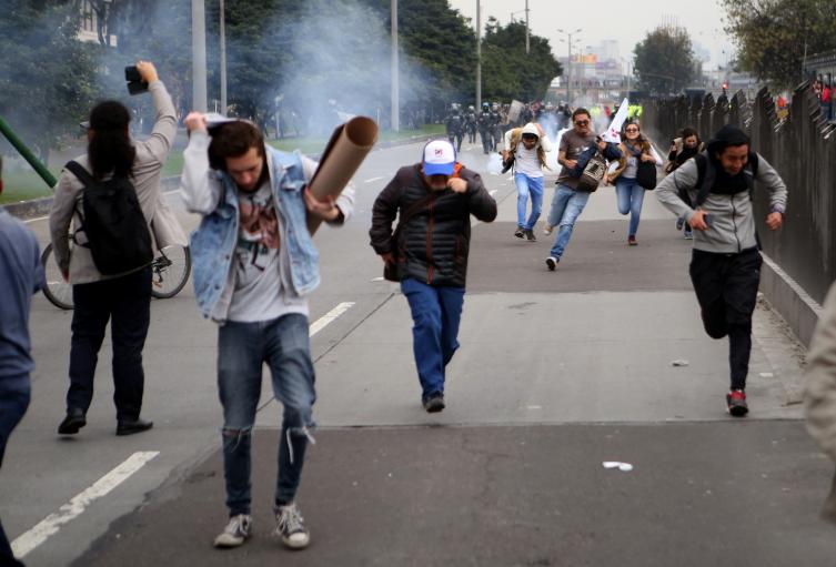 Varios estudiantes escapan de las bombas de aturdimiento del ESMAD