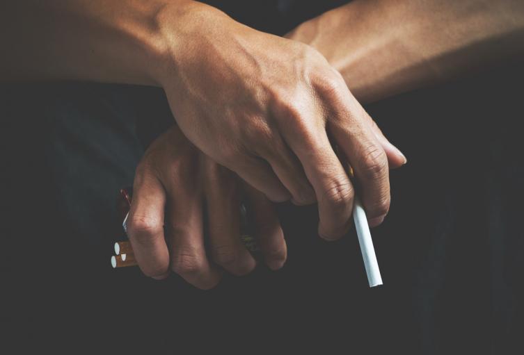 Un hombre sostiene cigarrillos en sus manos