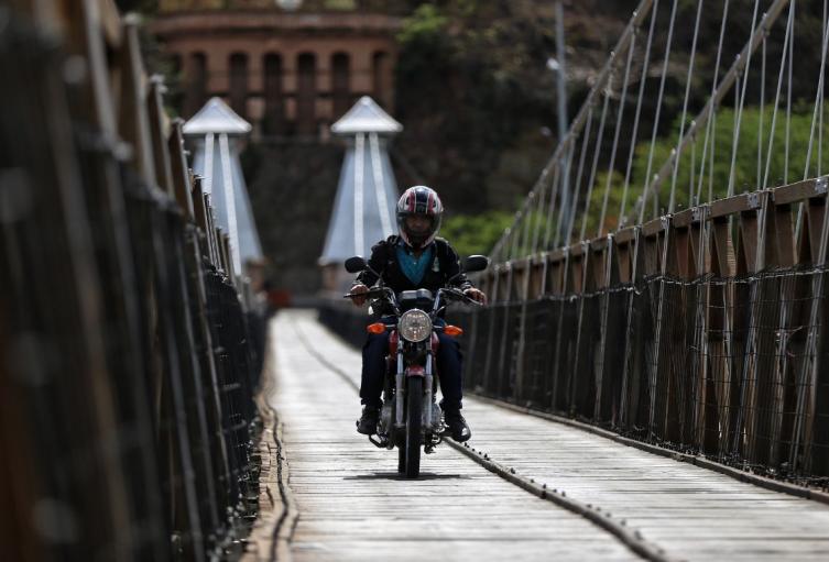 Viajes en moto por Colombia (imagen de referencia) Motociclista atravesando un puente en Colombia