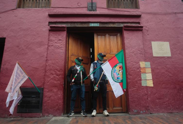 Dos integrantes de la Guardia Interétnica custodian la entrada del Ministerio de Vivienda en medio de las protestas del Congreso de los Pueblos en Bogotá.