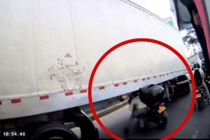 Motociclista tratando de pasar debajo de una tractomula en Bogotá