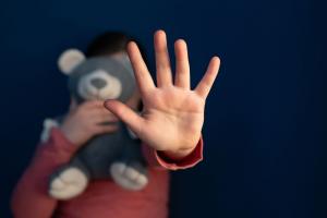 Menor tapándose la cara con un peluche