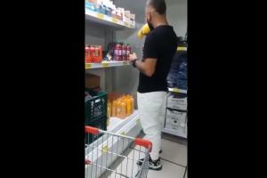 Hombre tomando de varias botellas de jugo en supermercado de Medellín